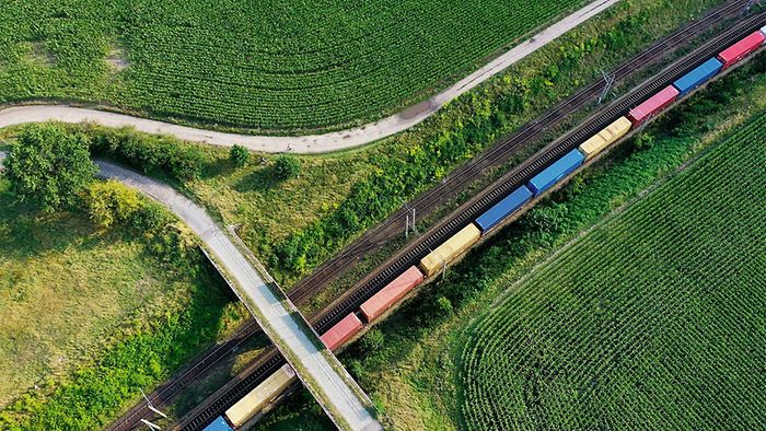 Freight train across green fields, top view