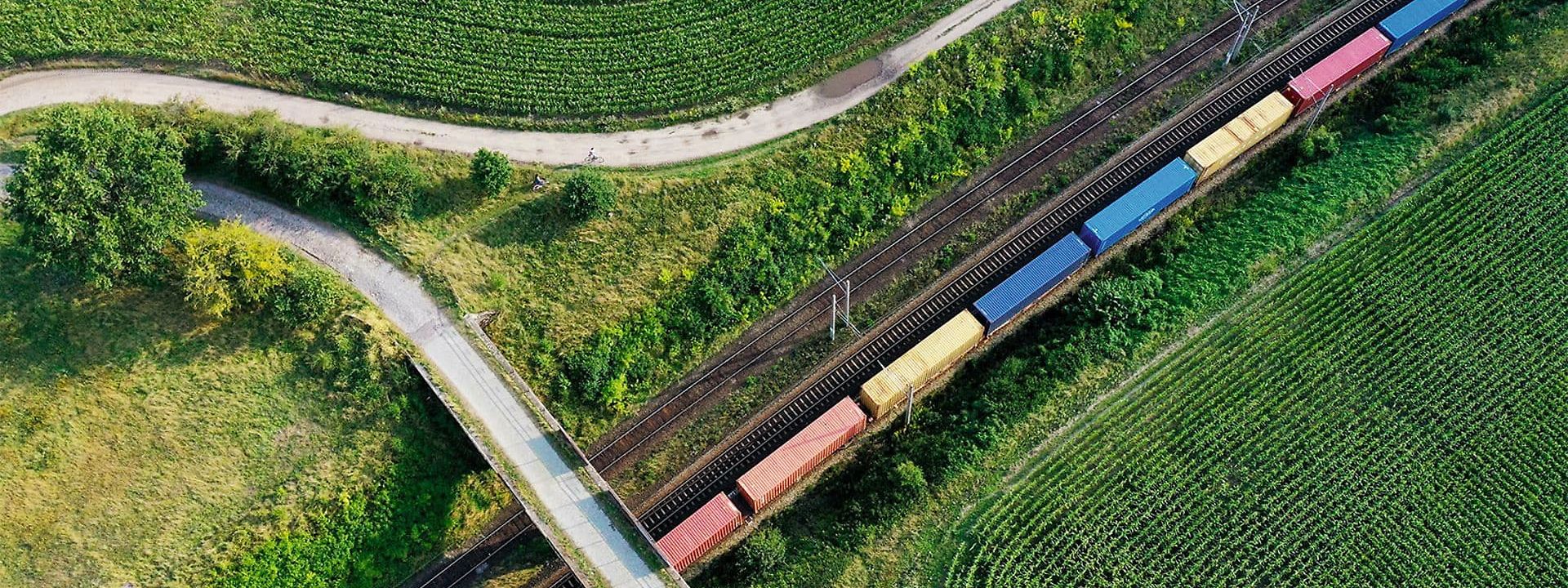 Freight train across green fields, top view